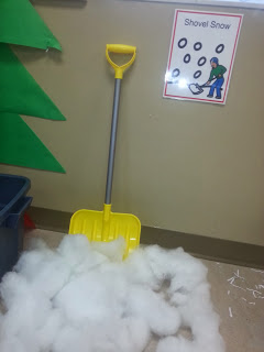 A pile of cotton stuffing on the ground with a shovel propped up next to it.