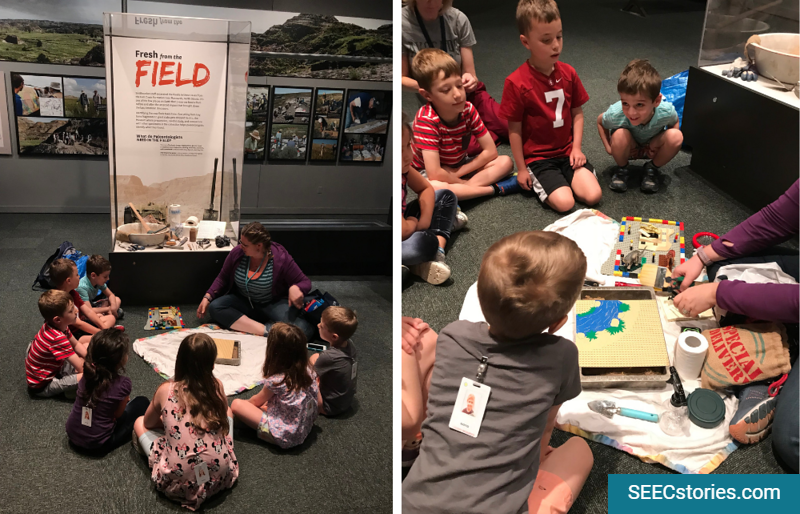 Children sitting in a circle looking at archaeology tools