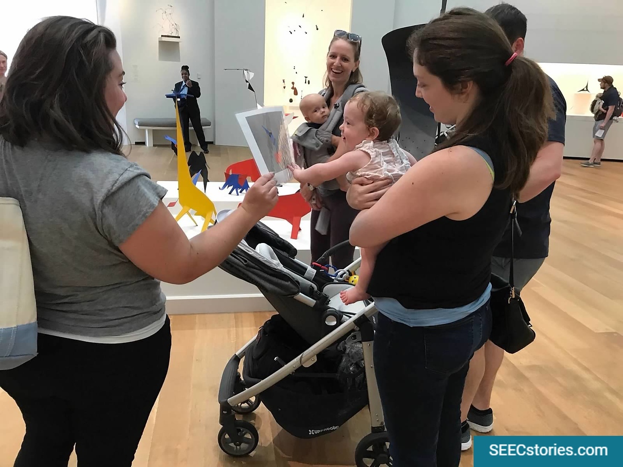Mother holding her child. The child pointing to a picture of a painting