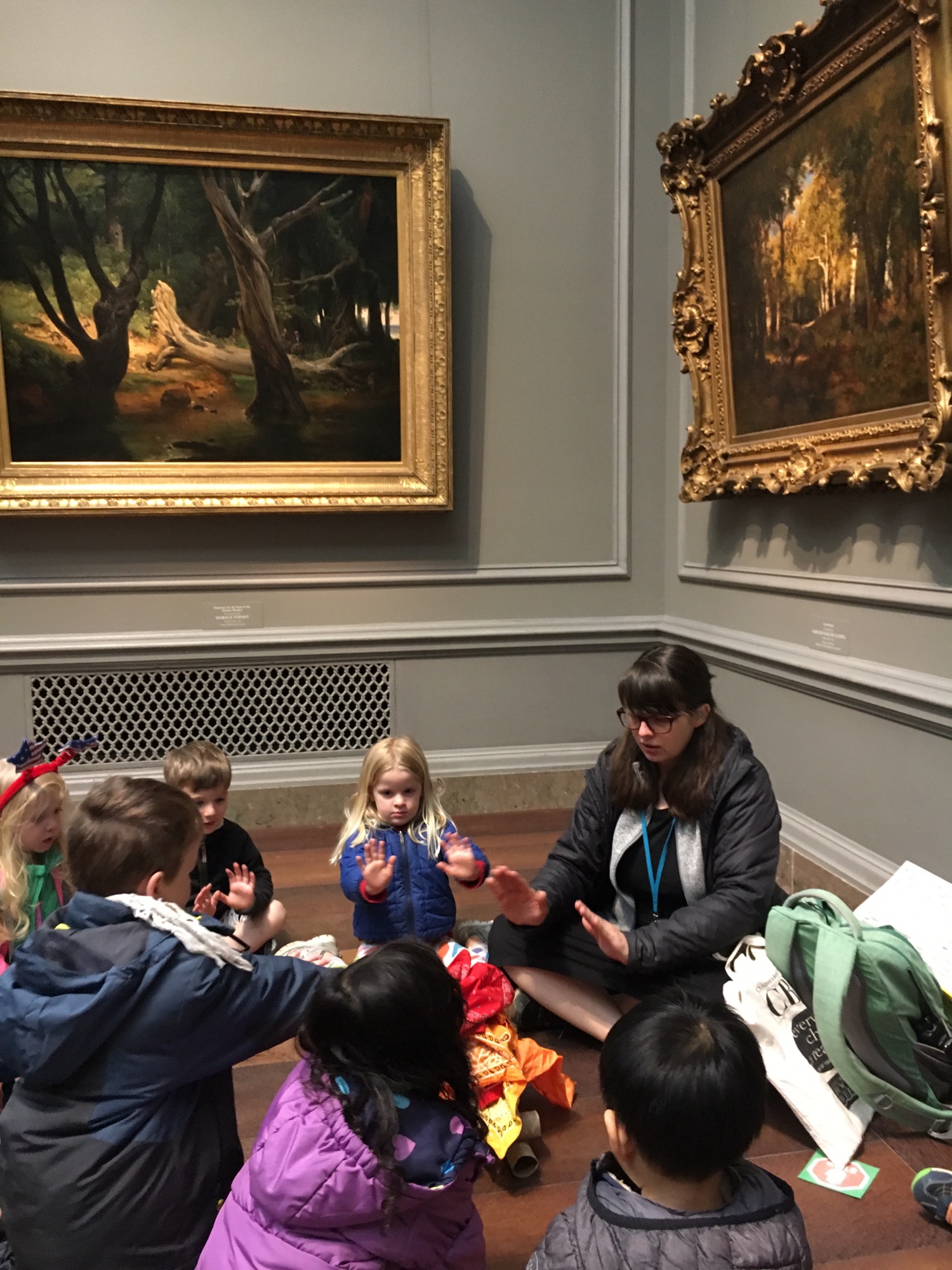 Children sitting in a circle around a pretend fire made out of fabric and cardboard. Trying to get warm