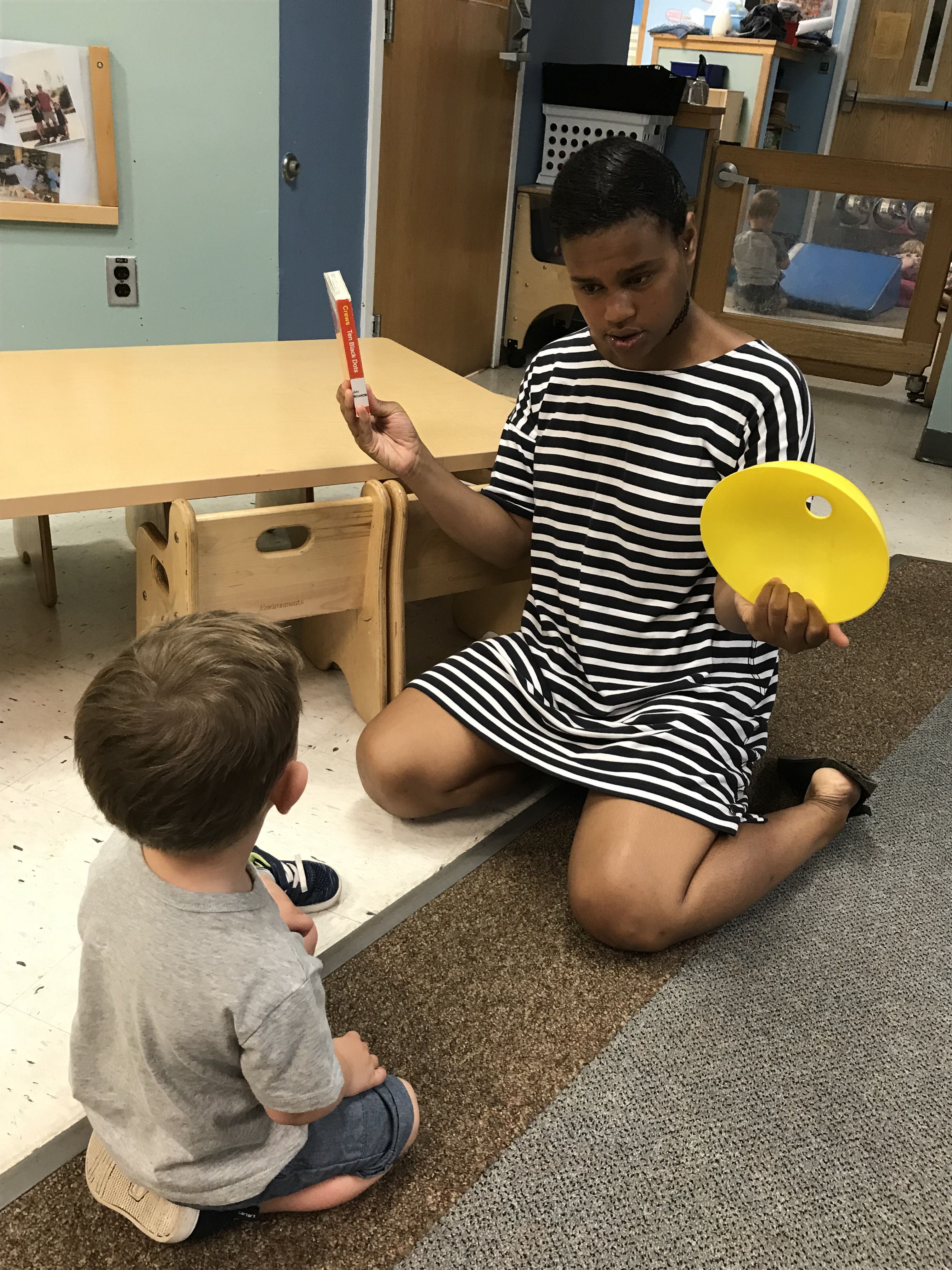 Teacher showing a child a toy and a book